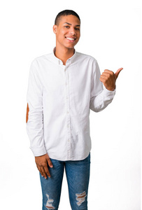 年轻的非洲裔美国人男子与白色衬衫指向侧面, 用手指来呈现一个产品或想法, 而期待在孤立的白色背景微笑