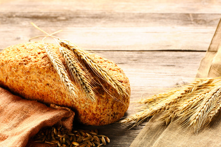 黑麦小穗和面包静物的木制背景