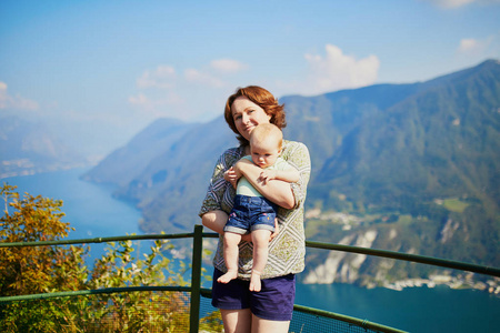 妇女与小女孩享受风景景色对卢加诺湖从山三萨尔瓦多在卢加诺, 提契诺, 瑞士。母亲与婴孩在看法点。与孩子一起旅行