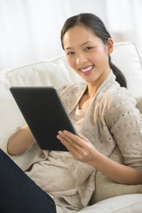 女人在沙发上放松的同时举行数字平板电脑
