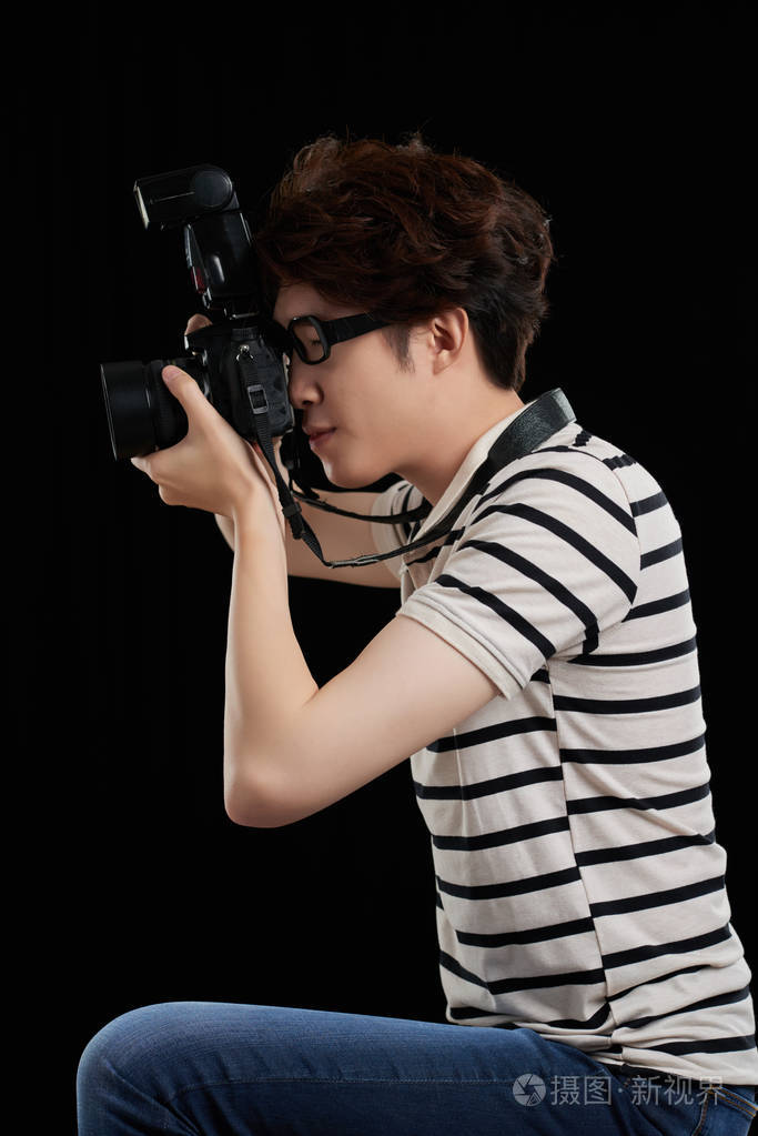 年轻摄影师的侧面图忙于工作