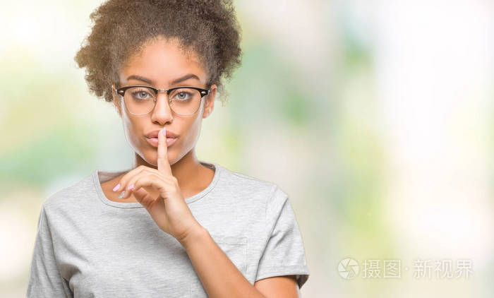 年轻的美国黑人妇女戴着眼镜在孤立的背景下, 要求在嘴唇上的手指安静。沉默和秘密概念