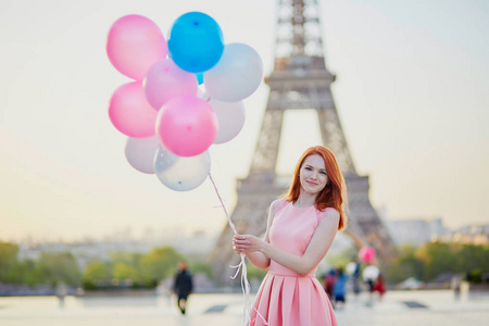 快乐的年轻女孩的粉色和蓝色气球在法国巴黎的埃菲尔铁塔前一堆
