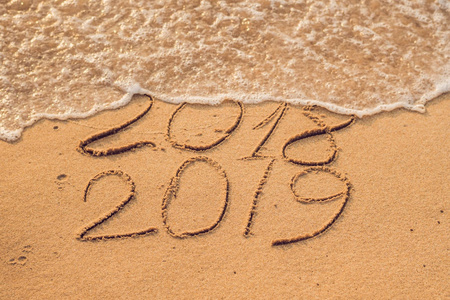 是写在沙子2019是未来概念-题字2018和2019在海滩沙子, 波浪几乎包括