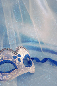 精致典雅的威尼斯面具在蓝色丝绸和薄纱面料背景的形象