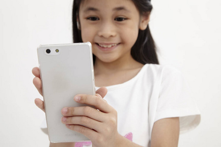 童年和技术。可爱的小女孩使用智能手机。隔离在白色
