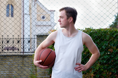 有魅力的男子拿着篮球, 看着远方