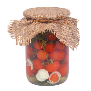 在白色上孤立的玻璃罐中腌制熟的西红柿