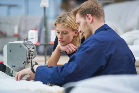 裁缝是新分配给一台机器在纺织厂, 工头解释的东西