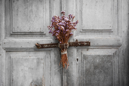 在希腊岛的一扇旧门上悬挂一束干花