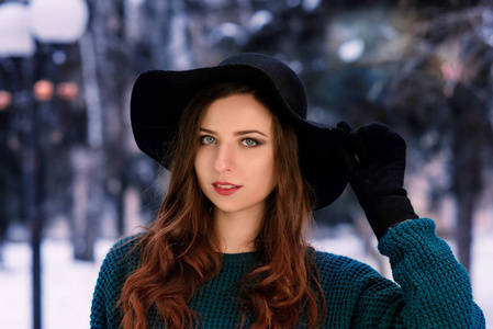 一个年轻漂亮的女孩在温暖的毛衣, 黑色的帽子特写肖像。少妇冬天画像