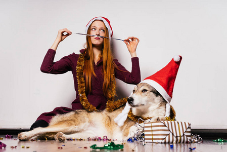 redhaired 美丽的女孩坐在地板上与她的狗, 等待新的一年, 许多明亮的金属箔