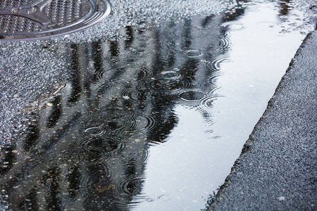 白色背景下水溅城市路面上的雨水坑照片