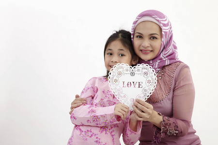 马来妇女与女儿抱着一个心形横幅一起