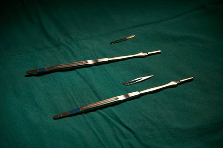 手术室绿表上两种不同尺寸的手术刀刀片和支架