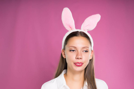 一个滑稽的女孩在白色衬衣和以兔子耳朵和嚼嚼口香糖的形式的边缘