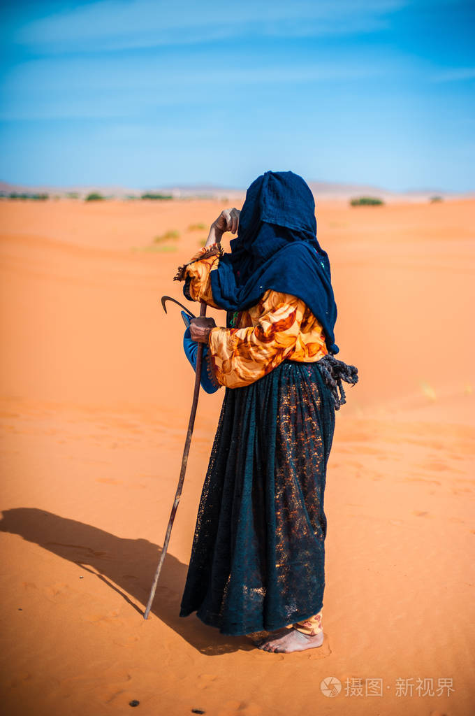 在摩洛哥梅尔祖卡一个沙丘上独自行走的老柏尔人妇女