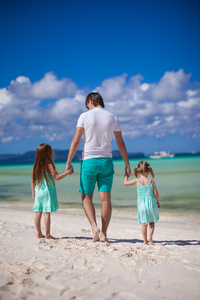 后视图的父亲和两个小女儿在海边散步