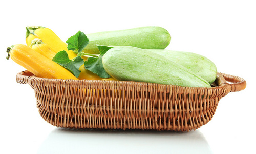 原料黄色和绿色西葫芦在柳条篮子里，在白色隔离