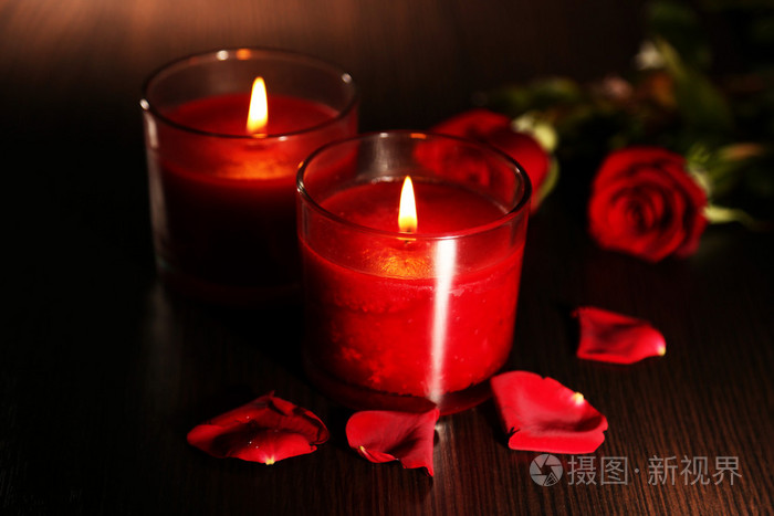 美丽浪漫红蜡烛与花瓣上黑的木制背景