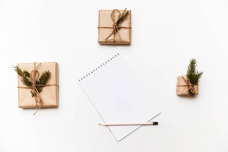 空白的笔记本, 铅笔和礼品盒或礼物包装在白色的牛皮纸隔离, 顶部视图