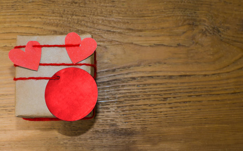 用一颗小小的心在木制背景下包装的礼物。情人节快乐