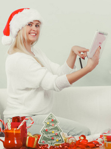 圣诞老人的帽子，拿着平板电脑和信用卡的女人