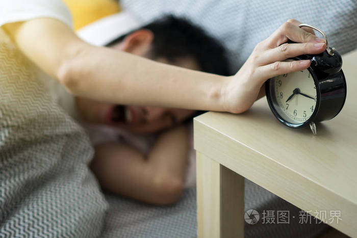 一个男人摸着关掉闹钟