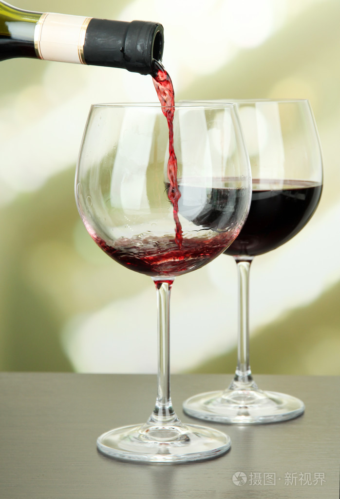 被注入到在明亮的背景上的红酒杯红酒