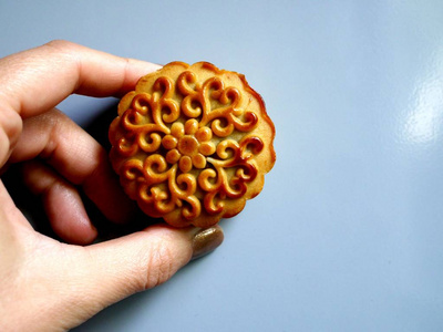 在一个女人的手上, 在上面有花卉点缀的月饼的照片。中秋节中国传统糕点