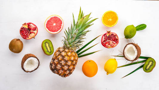 新鲜的热带水果。菠萝, 椰子, 猕猴桃, 橙, 石榴, 葡萄柚。在木制背景上。顶部视图。文本的可用空间