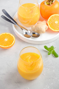 以柿橙姜为背景的新鲜健康的冰沙。选择性焦点