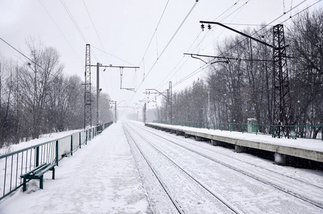 在寒冷的冬季, 铁路景观。大雪覆盖的火车站站台和大雾密布的天空