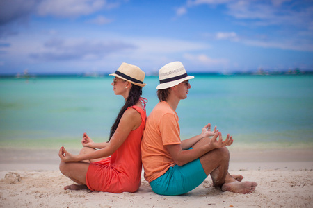 年轻夫妇享受彼此和瑜伽的沙滩上
