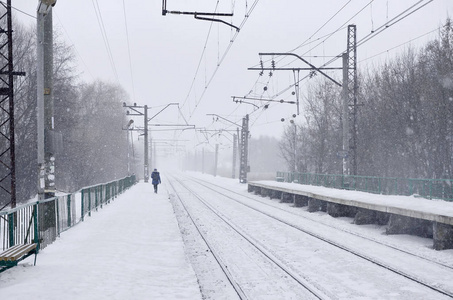 在寒冷的冬季, 铁路景观。大雪覆盖的火车站站台和大雾密布的天空