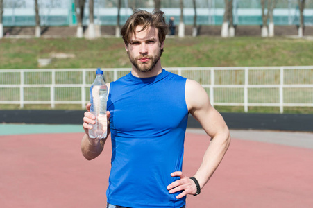 运动员男子手持塑料瓶喝水