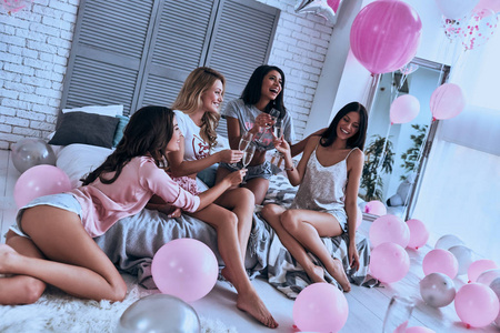 四具魅力的年轻女性穿着睡衣与香槟干杯, 在卧室与气球的聚会
