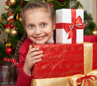 女孩与接近圣诞树 快乐的假期和冬季庆典礼品盒
