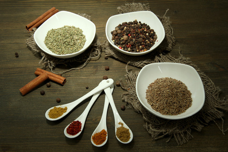 在白色的勺子和碗，木制背景上的香料的分类