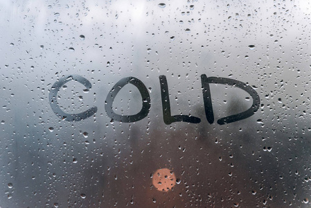 下雨的天气, 在汗的玻璃上的题词冷照片