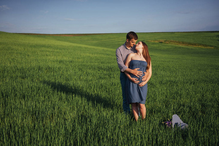 快乐的家庭拥抱在一个绿色的小麦领域。母亲在等待孩子。女人的笑脸, 男人