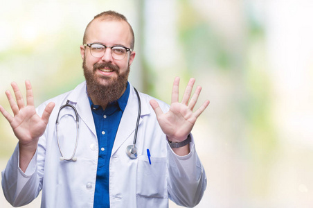 年轻的高加索医生男子穿着医疗白色外套在孤立的背景显示和手指指向数字十, 而微笑自信和快乐