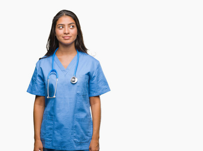 年轻的阿拉伯医生外科医生妇女在孤立的背景微笑地看着边和盯着思考