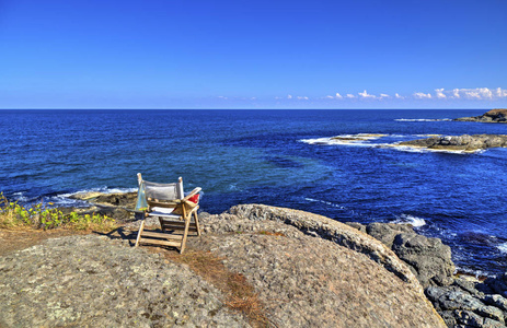 美丽的风景与木椅子在岩石海岸