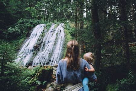 在森林瀑布附近的母亲与女儿