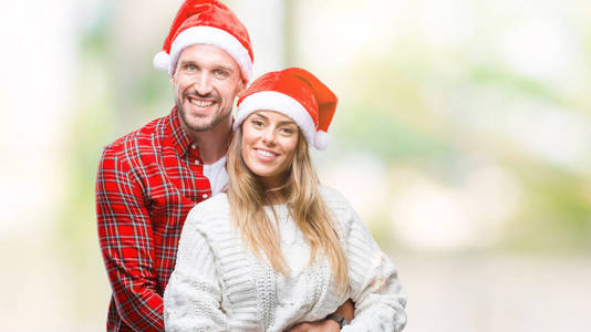 年轻夫妇在爱戴着圣诞节帽子在孤立的背景与一个愉快和凉爽的笑容在脸上。幸运的人