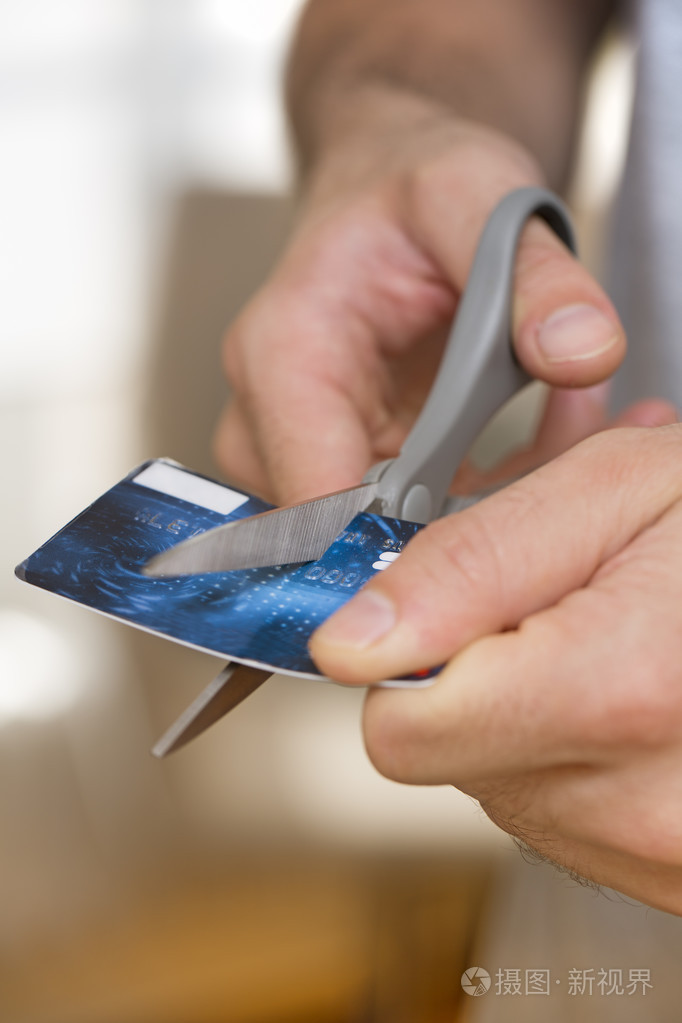 男人切割信用卡用剪刀的背景