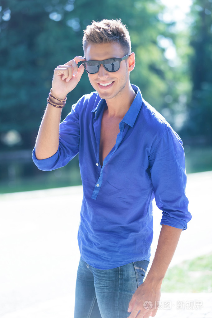 该名男子手持他的眼镜在自然中