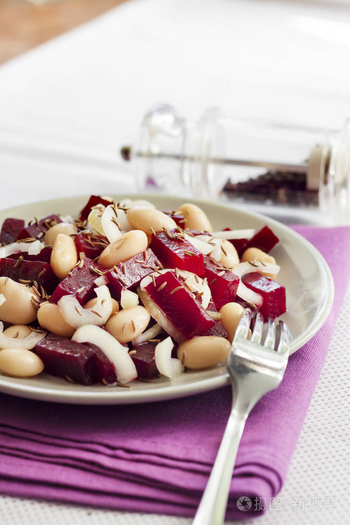 甜菜沙拉配白芸豆,泡菜和洋葱, 配上油, 用香菜籽调味.