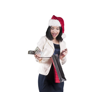 美丽的女孩在圣诞老人帽子红色购物袋孤立的钱